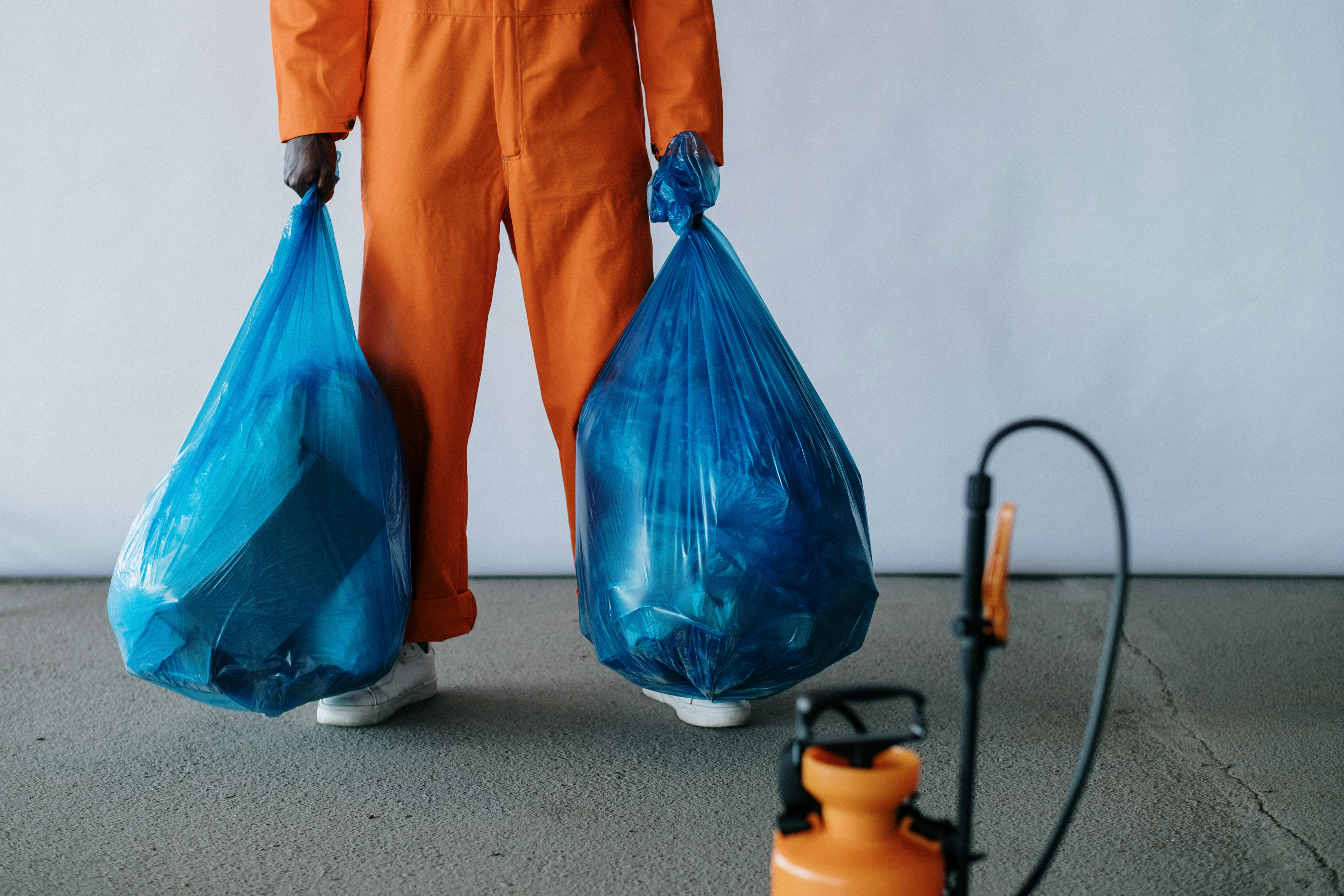 man holding trash bags full of home waste and cleaning supplies